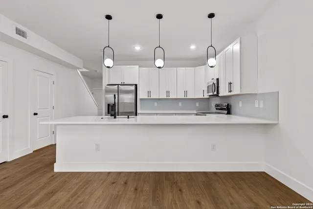 a kitchen with stainless steel appliances granite countertop a sink a window and wooden floor