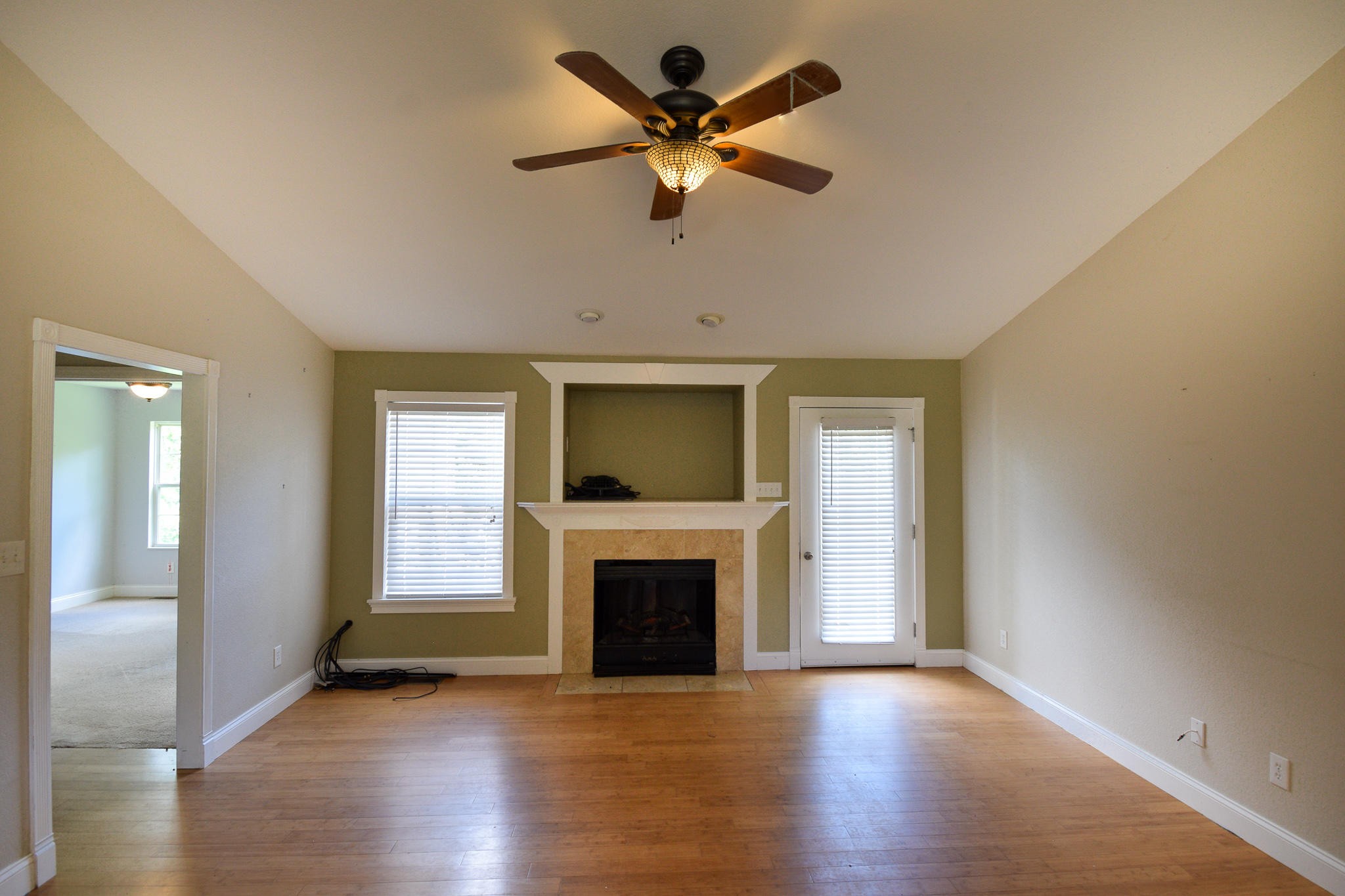 3328 Shagbark Road Powell, TN 37849 - Photo 8 of 32 an empty room with wooden floor a ceiling fan a fireplace and windows