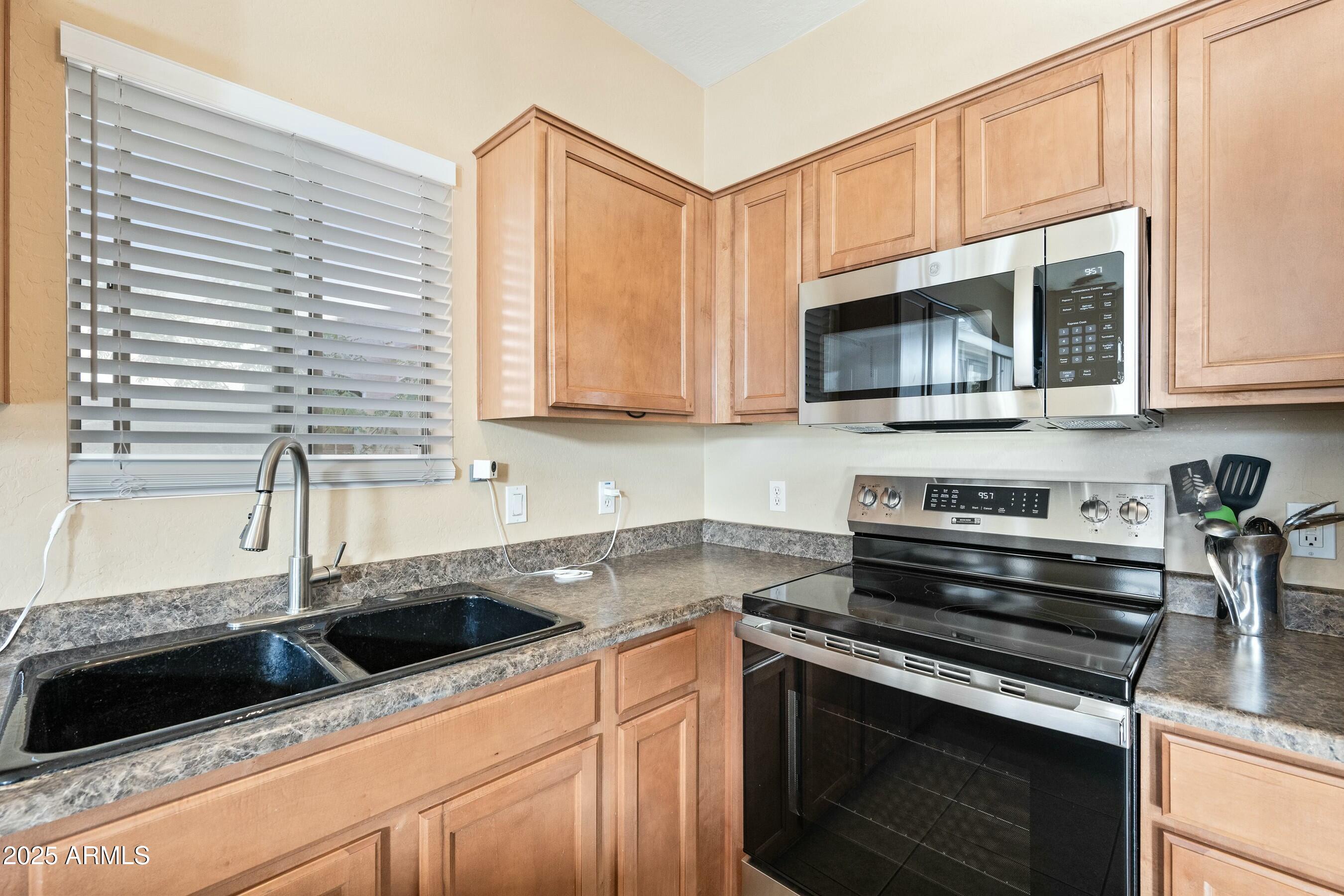 2150 East Bell Road, Unit 1130 Phoenix, AZ 85022 - Photo 8 of 39 a kitchen with granite countertop a sink dishwasher stove and microwave with wooden cabinets