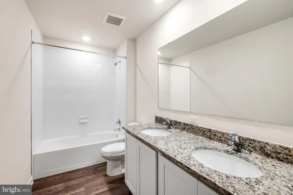 a bathroom with a granite countertop sink a toilet and shower