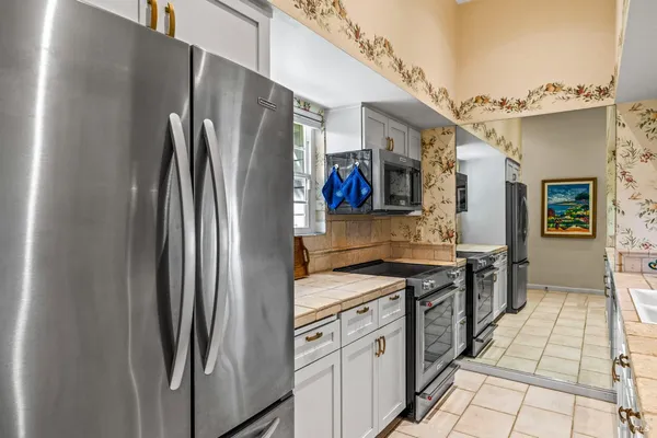 a kitchen with stainless steel appliances granite countertop a refrigerator a stove and a sink
