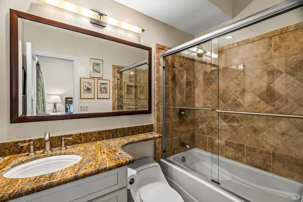 a bathroom with a granite countertop sink mirror toilet and bathtub
