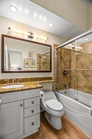 a bathroom with a toilet a sink a mirror a bathtub and shower