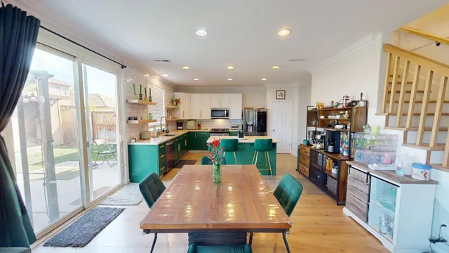 a living room with stainless steel appliances furniture a couch and a dining table
