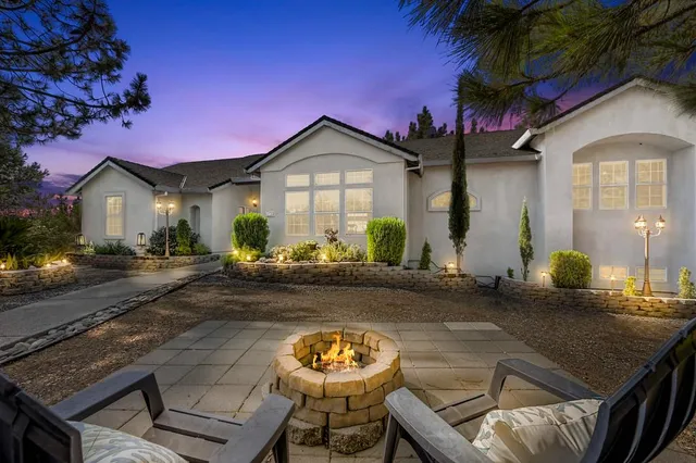 a view of a chairs and table in a patio next to a yard