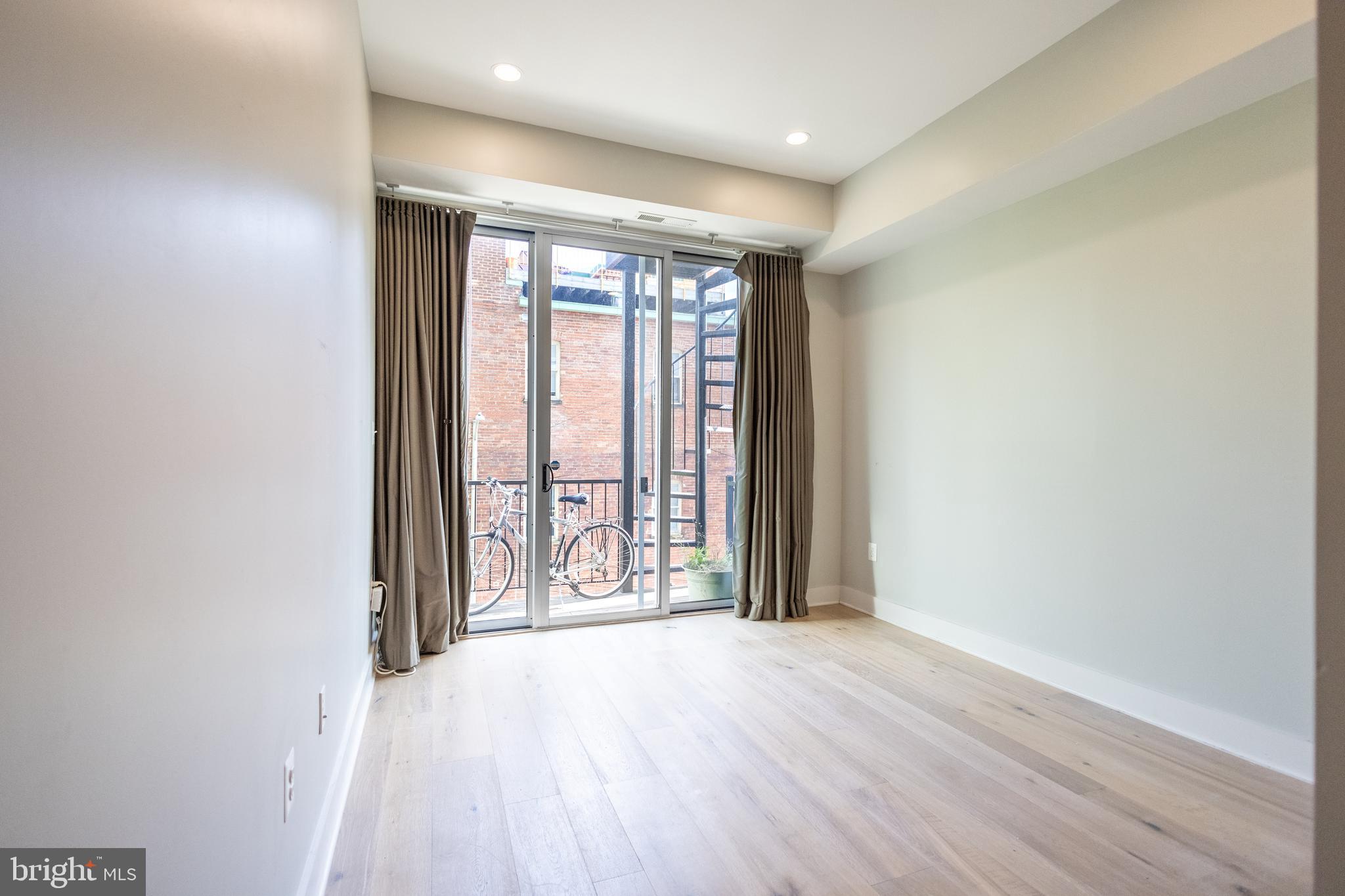 1476 Harvard Street Northwest, Unit C Washington, DC 20009 - Photo 4 of 20 an empty room with wooden floor and door