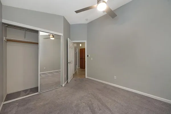 an empty room with closet and a chandelier fan