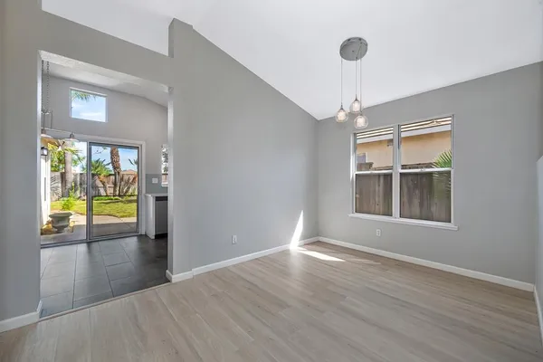 a view of an empty room with window and wooden floor
