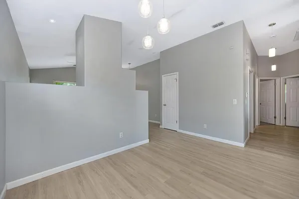 an empty room with wooden floor and windows