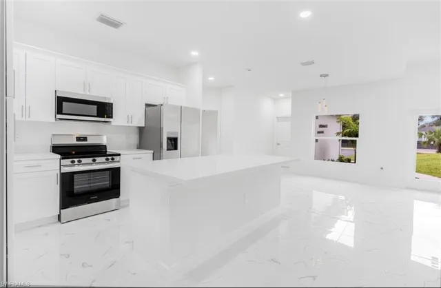 a large white kitchen with cabinets and a refrigerator