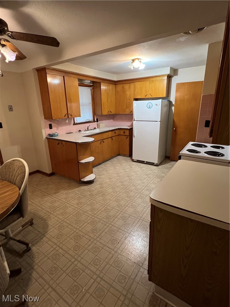 11406 Granger Road Cleveland, OH 44125 - Photo 3 of 28 Kitchen with ceiling fan, sink, kitchen peninsula, stove, and fridge