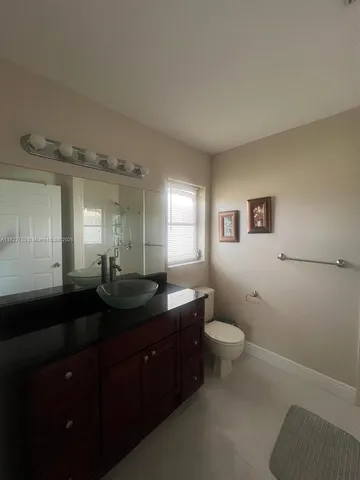 a bathroom with a granite countertop sink toilet and mirror