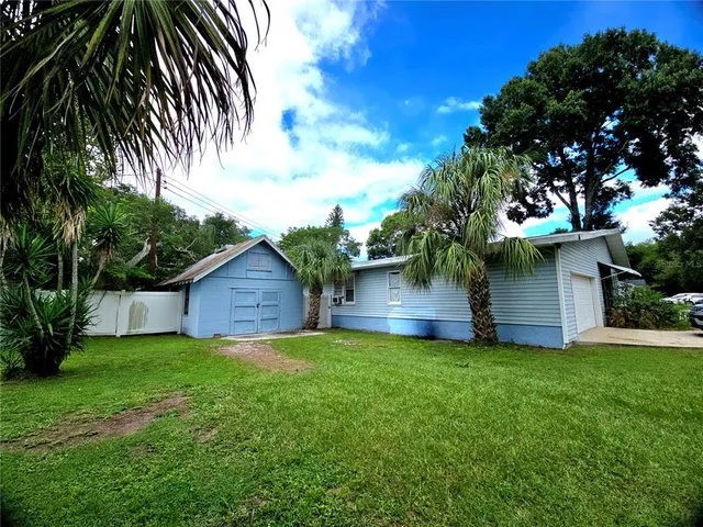 a view of a house with a yard and a large tree