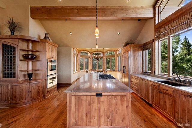 a kitchen with stainless steel appliances granite countertop a sink a stove and a wooden floors