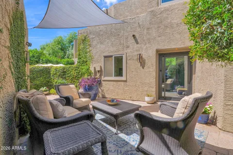 a view of a patio with couches table and chairs under an umbrella