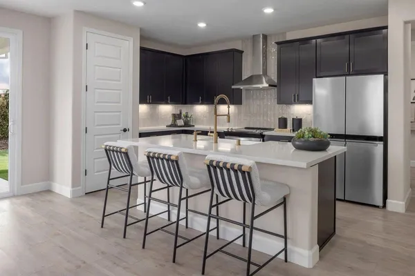 a kitchen with stainless steel appliances granite countertop a table chairs microwave and sink