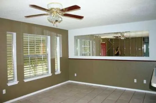 a view of an empty room with a window and a chandelier fan