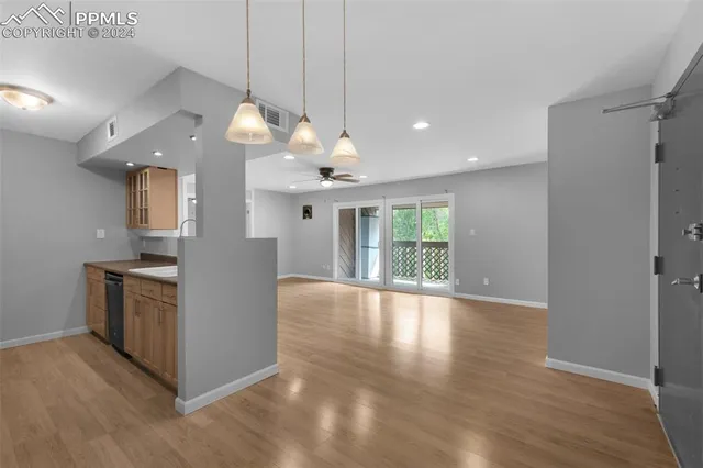 a view of an empty room with window and wooden floor