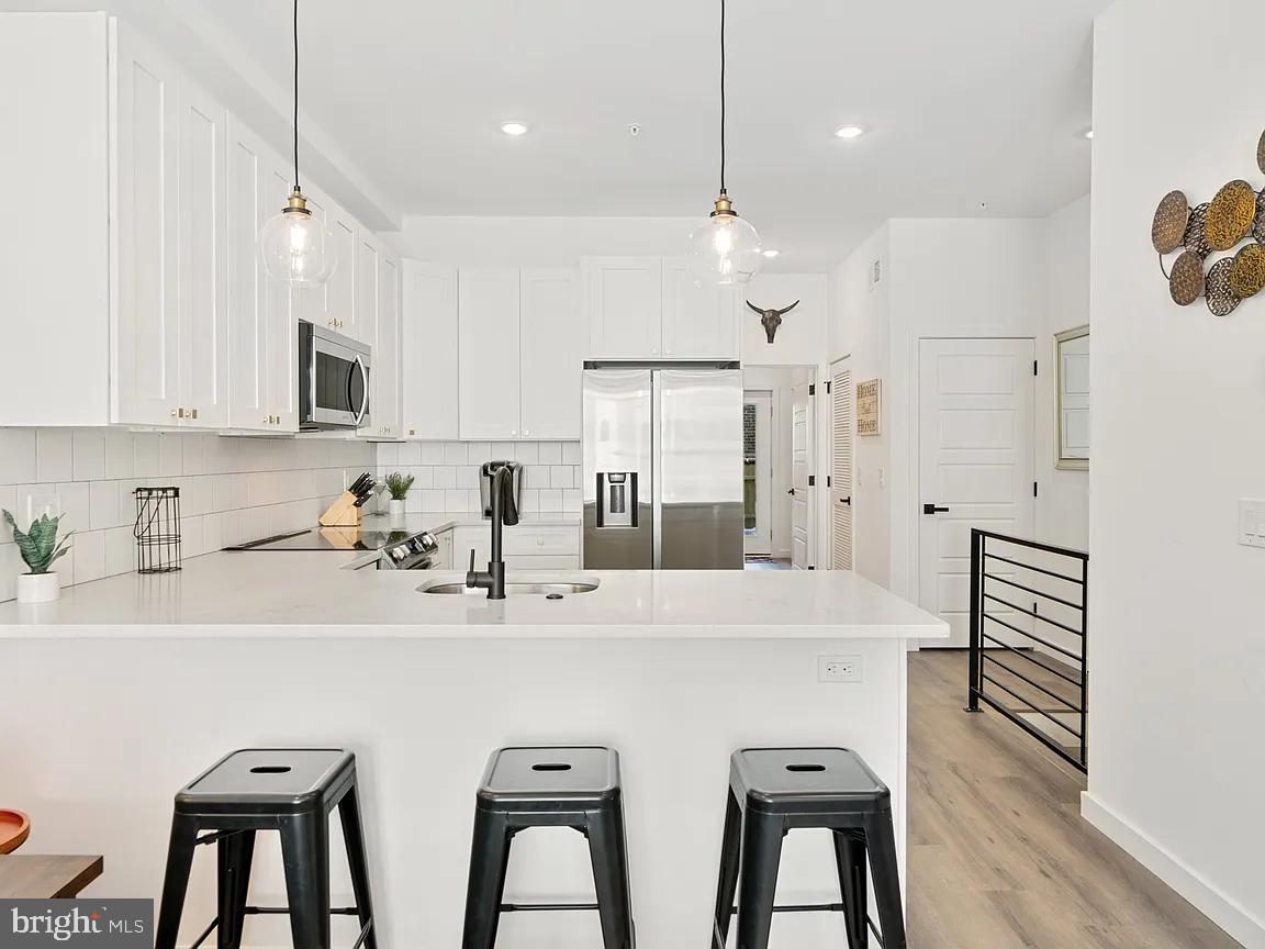 1735 South 23rd Street, Unit 2 Philadelphia, PA 19145 - Photo 5 of 17 a kitchen with stainless steel appliances kitchen island a table chairs refrigerator and microwave