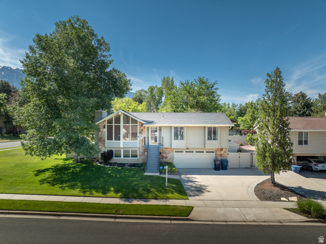2088 Falcon Way Sandy, UT 84093 - Photo 1 of 46 Split-level residence featuring a prominent gabled sunroom with large windows, a two-car garage, and a wide concrete driveway