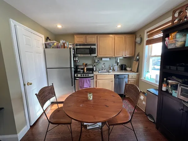 a room with stainless steel appliances a dining table chairs refrigerator and a sink