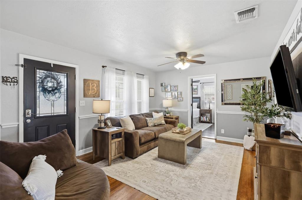 308 West 1st Street Springtown, TX 76082 - Photo 9 of 39 Living area featuring wood-finish flooring, light gray walls with chair rail molding, and a ceiling fan