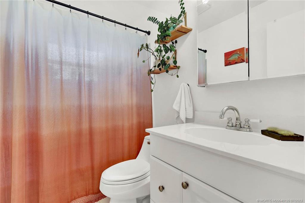 1790 Southeast Madison Street Stuart, FL 34997 - Photo 15 of 24 a bathroom with a sink a toilet and shower curtain
