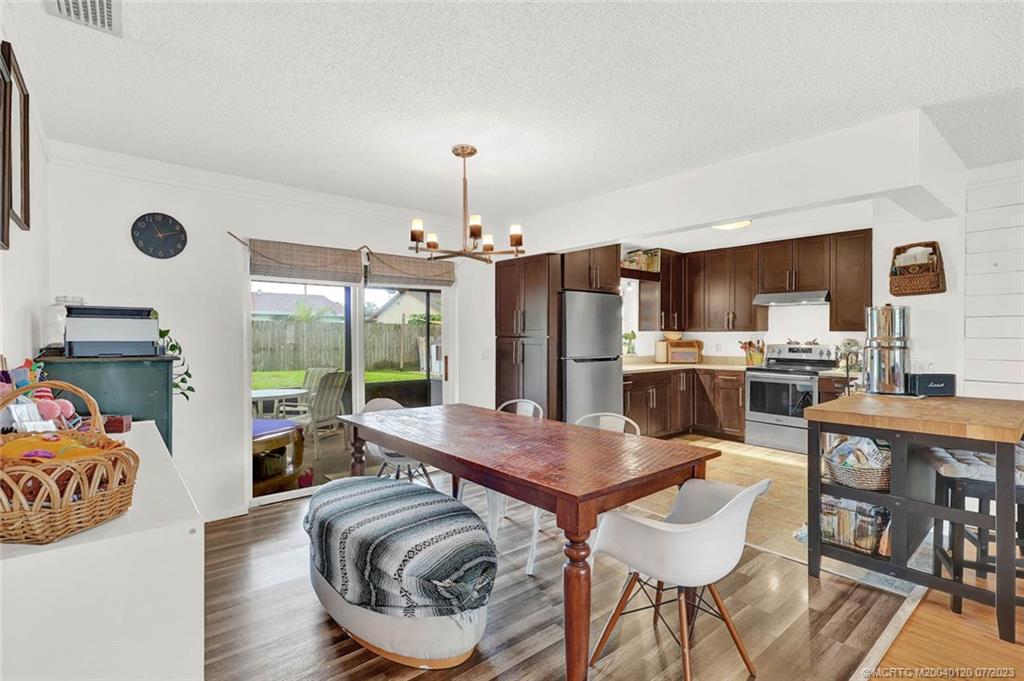 1790 Southeast Madison Street Stuart, FL 34997 - Photo 6 of 24 a kitchen with stainless steel appliances kitchen island granite countertop a refrigerator a stove a oven a sink with island chairs and wooden floor