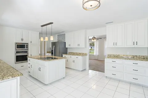 a kitchen with granite countertop white cabinets and white appliances