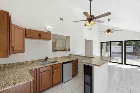 a kitchen with kitchen island granite countertop a sink a counter top space appliances and cabinets
