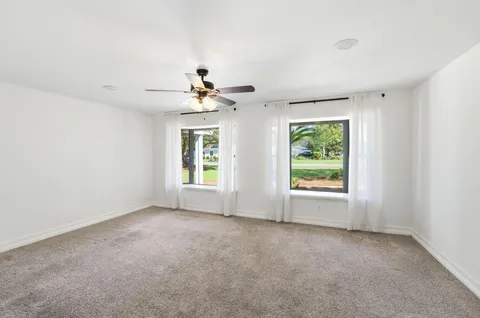 an empty room with windows and chandelier fan