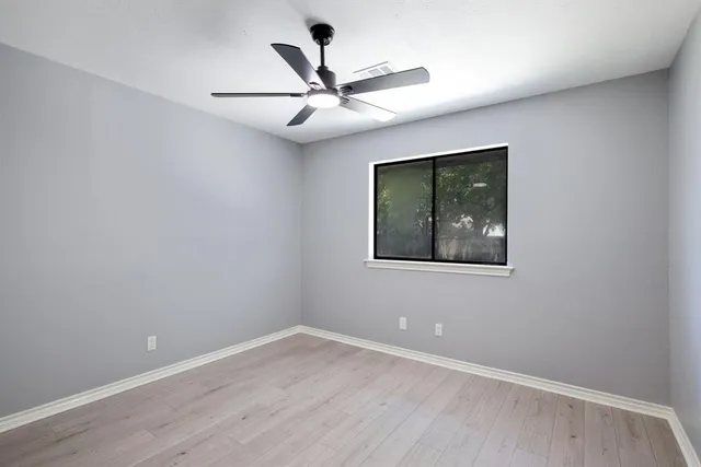 an empty room with a window and a fan