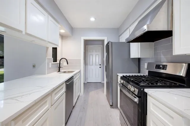 a kitchen with granite countertop a sink a stove and refrigerator