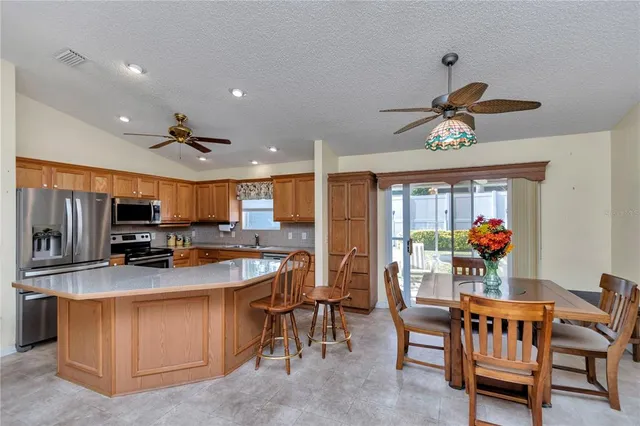 a kitchen view with stainless steel appliances kitchen island granite countertop a sink and a refrigerator