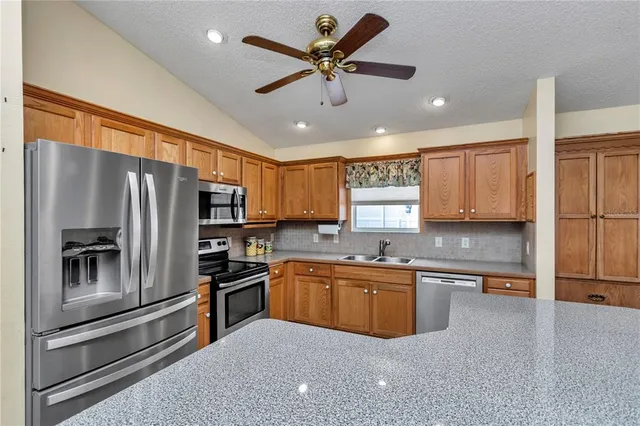 a kitchen with stainless steel appliances a sink a stove a refrigerator cabinets and a counter top space