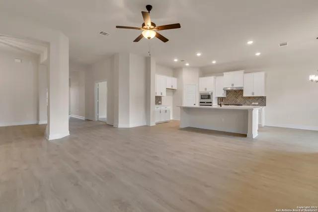a view of a kitchen with a stove cabinets a ceiling fan and wooden floor