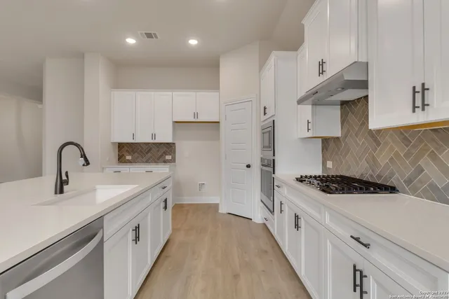 a kitchen with stainless steel appliances a stove a sink and a refrigerator