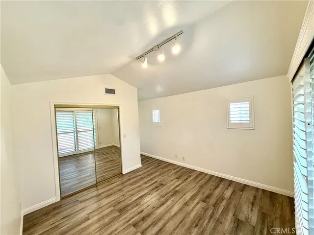 a walk in closet with wooden floor