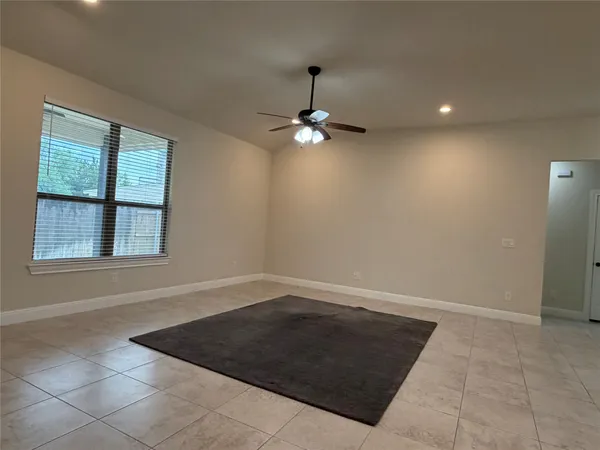 an empty room with a ceiling fan and window