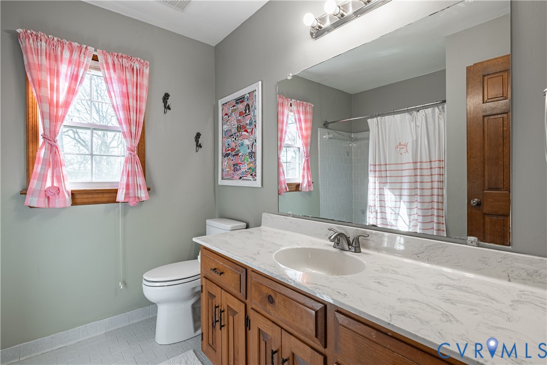 5307 Krag Road Chester, VA 23831 - Photo 42 of 49 a bathroom with a granite countertop sink a toilet a mirror and a window
