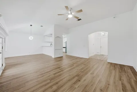 a view of empty room with wooden floor and fan