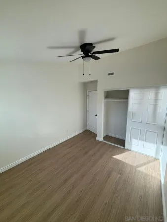 a view of empty room with wooden floor and fan