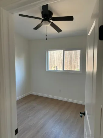 an empty room with wooden floor fan and windows