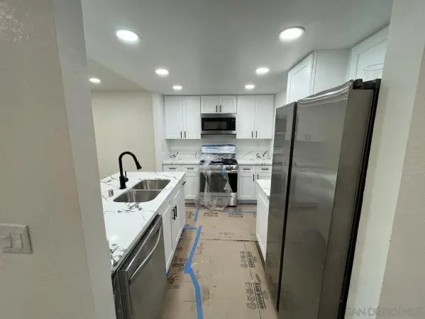 a kitchen with stainless steel appliances granite countertop a refrigerator a sink a stove a microwave and a refrigerator