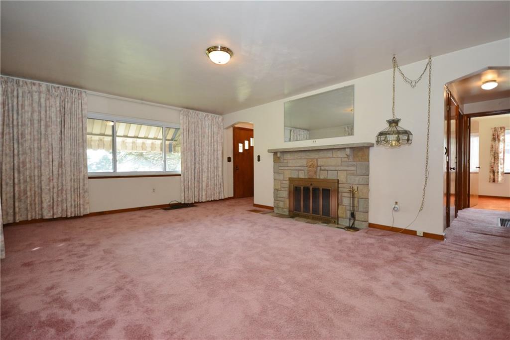 1034 Silver Lane McKees Rocks, PA 15136 - Photo 3 of 25 The living room is generously sized, and offers a large picture window overlooking the front of the home, and a fireplace with stone surround. There are hardwood floors beneath most of the carpeting throughout the home. On the right side of the photo, the closed door leading to the lower level can be seen.