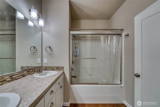 a bathroom with a granite countertop sink a mirror and a bathtub