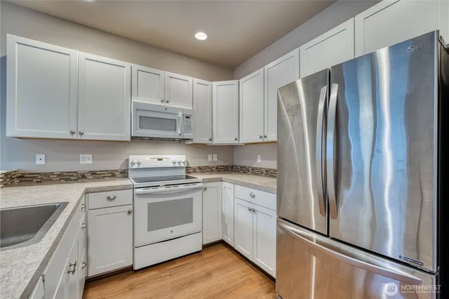 a kitchen with stainless steel appliances white cabinets and a refrigerator
