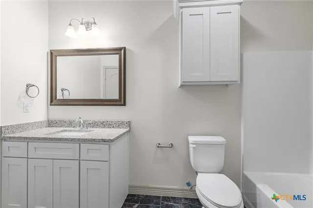 a bathroom with a granite countertop toilet sink and mirror