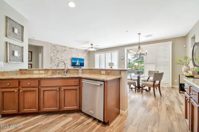 a kitchen with stainless steel appliances granite countertop a table chairs stove and refrigerator