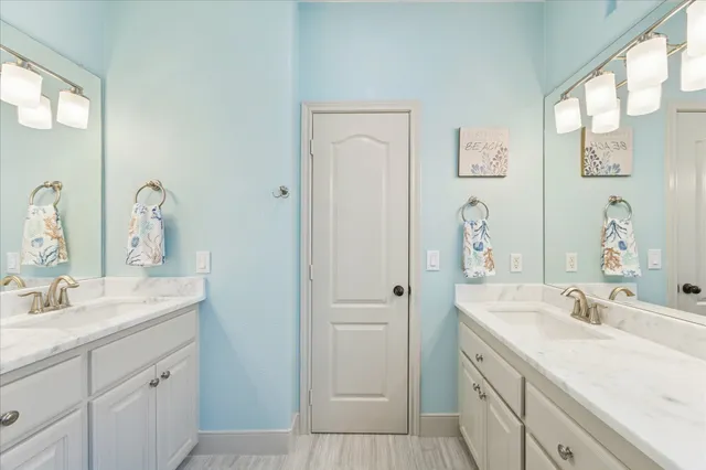 a bathroom with a granite countertop double vanity sink a mirror and a toilet